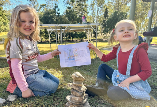 Two girls holding a map in front of a rock stack