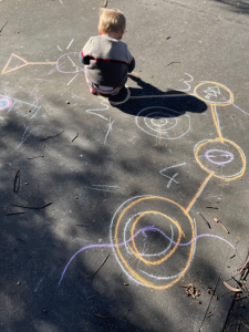 Participant drawing an orienteering course on a pavement with chalk.